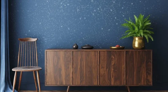 parede com glitter em azul com aparador de madeira com planta em vaso de metal dourado em cima