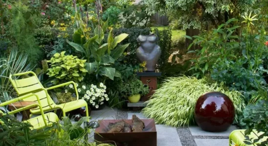 como decorar um jardim pequeno com plantas de diversas espécies, cadeiras, lareira, fonte circular de pedra, escultura e chão de pedras.
